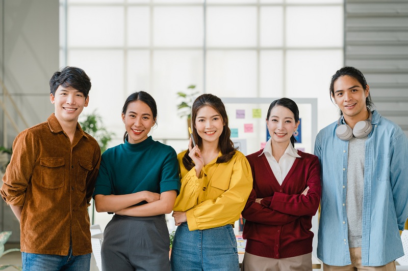Young diverse Gen Z employees collaborating in a modern office setting with laptops and relaxed atmosphere.