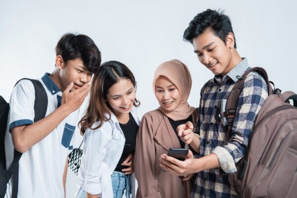 Kegiatan Kampus yang Wajib dicoba sebagai Mahasiswa Baru! Mahasiswa baru tersenyum sambil membawa buku dan laptop, berjalan di area kampus dengan suasana ceria.