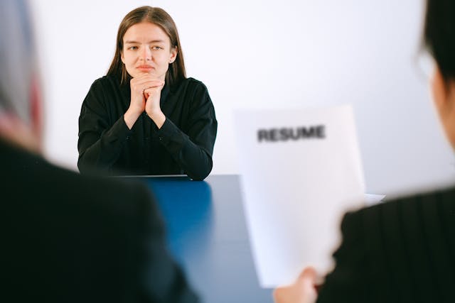 A young woman attending a job interview while recruiters review her resume during an interview session.