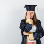 Fresh graduate mengenakan toga terlihat sedih dan bingung setelah lulus kuliah, menggambarkan kondisi post graduation depression pada fresh graduate.