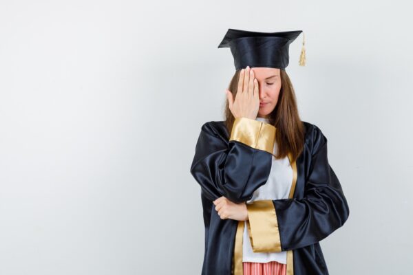 Fresh graduate mengenakan toga terlihat sedih dan bingung setelah lulus kuliah, menggambarkan kondisi post graduation depression pada fresh graduate.