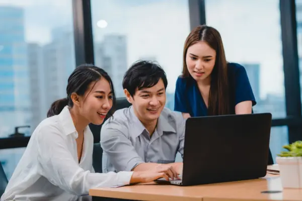Fresh graduate sedang berdiskusi di kantor sambil melihat laptop untuk mencari peluang loker entry level dan memulai karier pertama