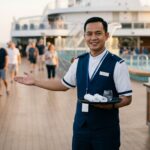 Pekerja hospitality kapal pesiar membawa nampan di area deck cruise ship