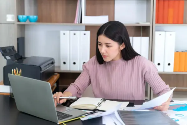 Seorang wanita muda berbaju pink yang sedang membuat dummy project data entry untuk pemula