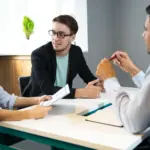 tiga orang yang sedang berdiskusi sedang mewawawancarai fresh graduate cara menjawab interview