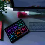Setup desainer grafis dengan tablet menampilkan ikon Adobe Premiere, After Effects, Photoshop, dan Illustrator di atas meja studio kreatif.